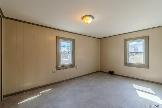 empty room featuring a wealth of natural light, visible vents, baseboards, and concrete flooring