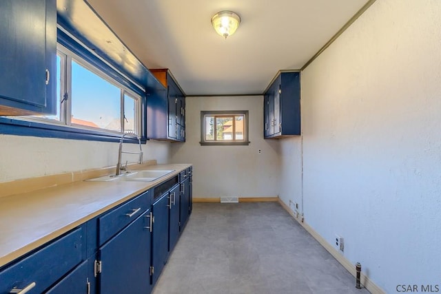 kitchen with visible vents, blue cabinets, baseboards, and a sink