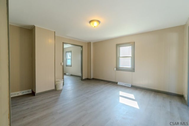 unfurnished room with wood finished floors, visible vents, and baseboards