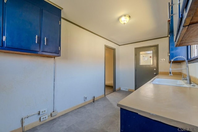 kitchen with blue cabinetry, baseboards, and a sink