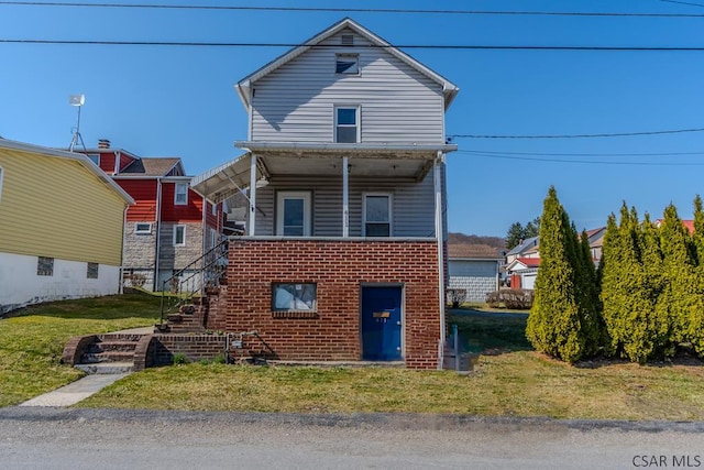 traditional-style house featuring brick siding, stairs, and a front lawn