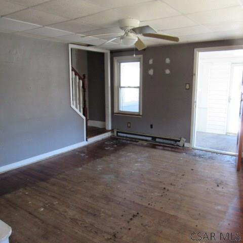 418 Main St, Vintondale, PA 15961 - empty room with baseboards, ceiling fan, wood finished floors, stairs, and baseboard heating