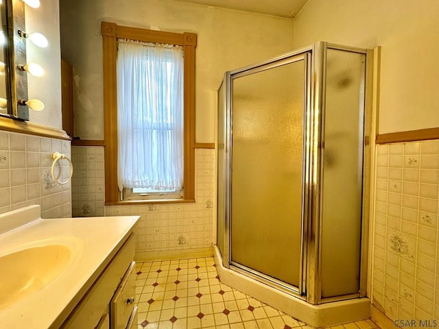 full bath featuring tile walls, vanity, tile patterned floors, a shower stall, and wainscoting