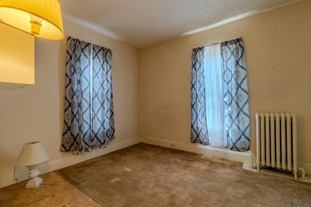 unfurnished room with baseboards and radiator heating unit