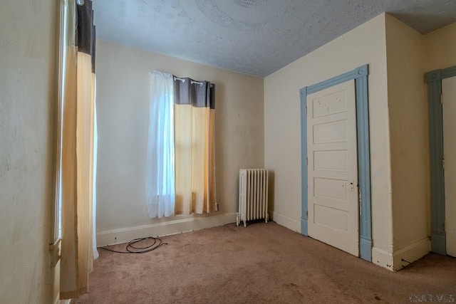 empty room with baseboards, radiator heating unit, and carpet