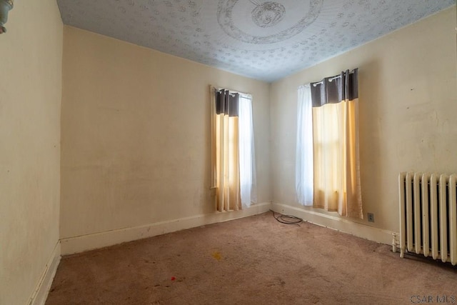 unfurnished room featuring baseboards, radiator heating unit, and carpet floors