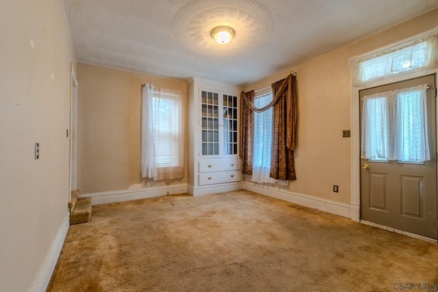foyer featuring carpet floors, baseboards, and a healthy amount of sunlight