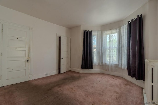 carpeted spare room with baseboards and radiator heating unit