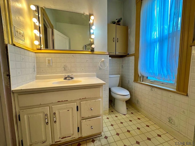 bathroom with toilet, tile walls, tile patterned floors, and vanity