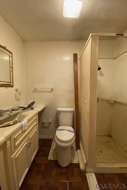 bathroom featuring toilet, a shower, a textured ceiling, parquet floors, and vanity