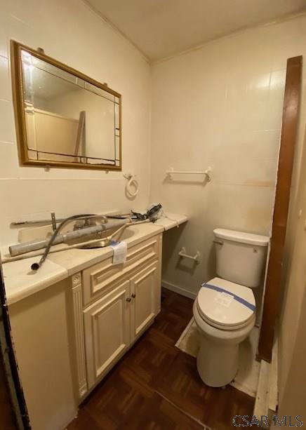 bathroom with parquet flooring, vanity, and toilet