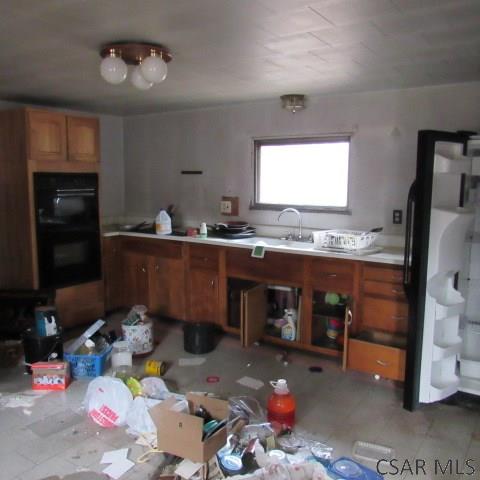 kitchen with brown cabinetry, light countertops, dobule oven black, and a sink