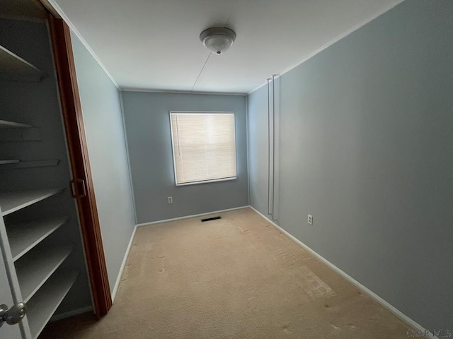 carpeted empty room featuring crown molding