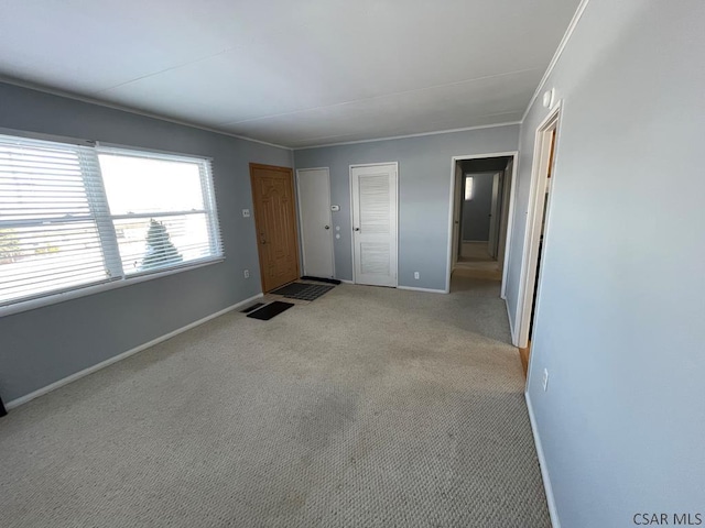 empty room featuring crown molding and light colored carpet