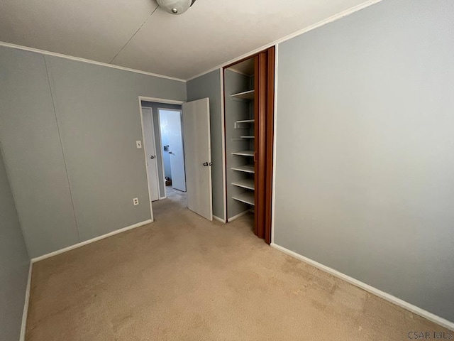 unfurnished bedroom with ornamental molding, light colored carpet, and a closet