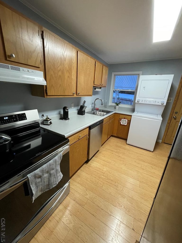 kitchen featuring sink, stacked washing maching and dryer, light hardwood / wood-style floors, and appliances with stainless steel finishes