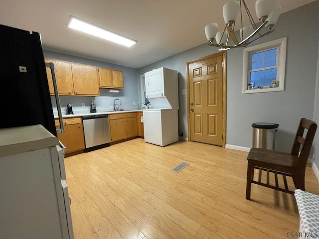 kitchen with black refrigerator, sink, stacked washer / drying machine, stainless steel dishwasher, and light hardwood / wood-style flooring