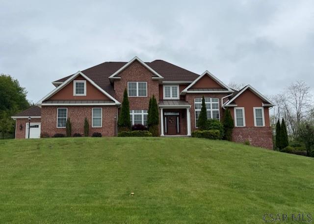 view of front facade with a front lawn, brick siding, and a garage