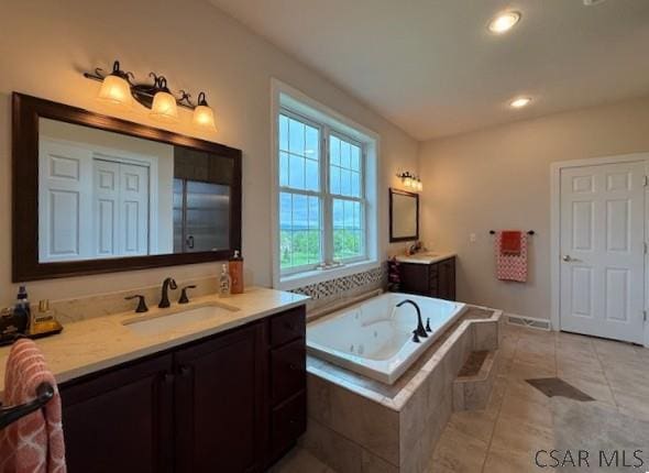 bathroom with tile patterned flooring, two vanities, a bath, and recessed lighting