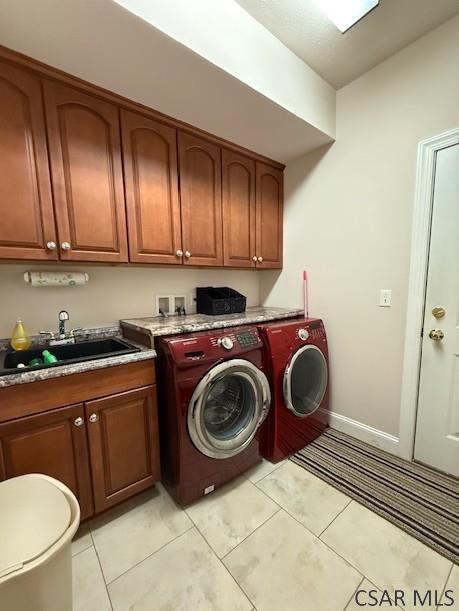 laundry area with washer and dryer, cabinet space, baseboards, and light tile patterned floors