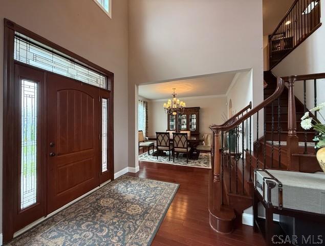 entryway featuring stairs, wood finished floors, a chandelier, a high ceiling, and baseboards