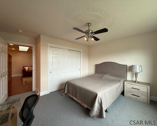bedroom featuring carpet, a closet, baseboards, and a ceiling fan