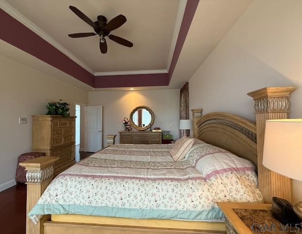 bedroom featuring crown molding, dark wood-style floors, a raised ceiling, baseboards, and ceiling fan