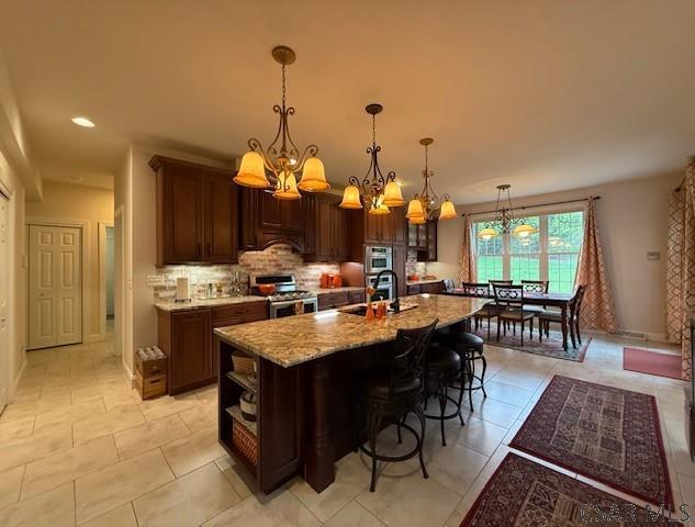 kitchen with stainless steel range, a sink, a chandelier, decorative backsplash, and open shelves