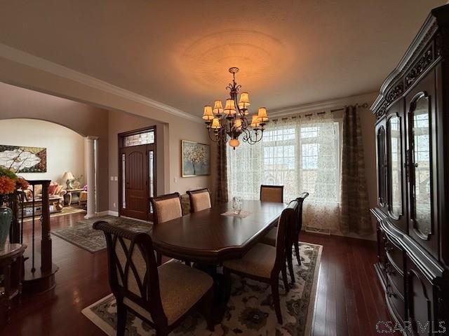 dining space featuring a chandelier, arched walkways, dark wood-style flooring, crown molding, and baseboards