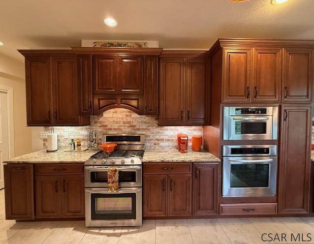 kitchen with stainless steel appliances, backsplash, light stone countertops, recessed lighting, and light tile patterned floors