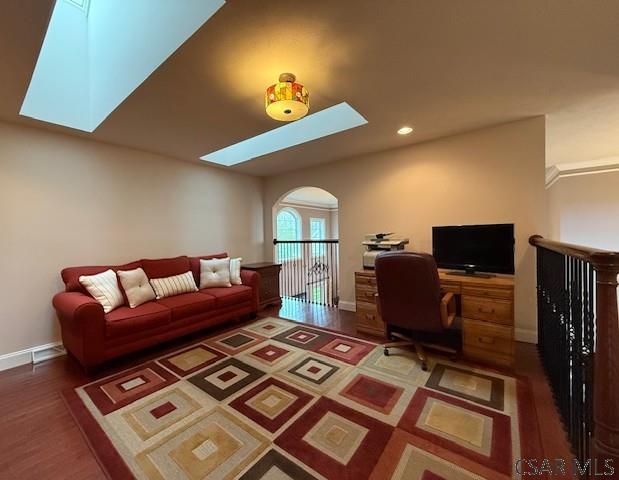 office space with a skylight, wood finished floors, arched walkways, baseboards, and recessed lighting