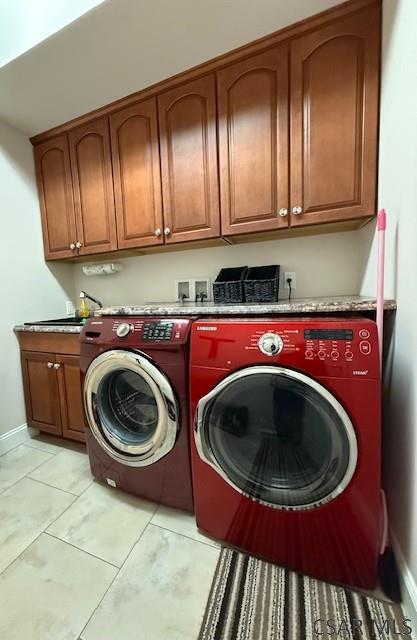 washroom with cabinet space, washer and dryer, and baseboards