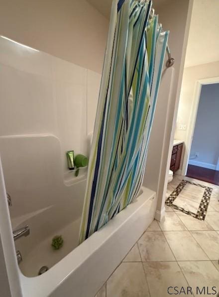 full bathroom with shower / tub combo, tile patterned flooring, and toilet