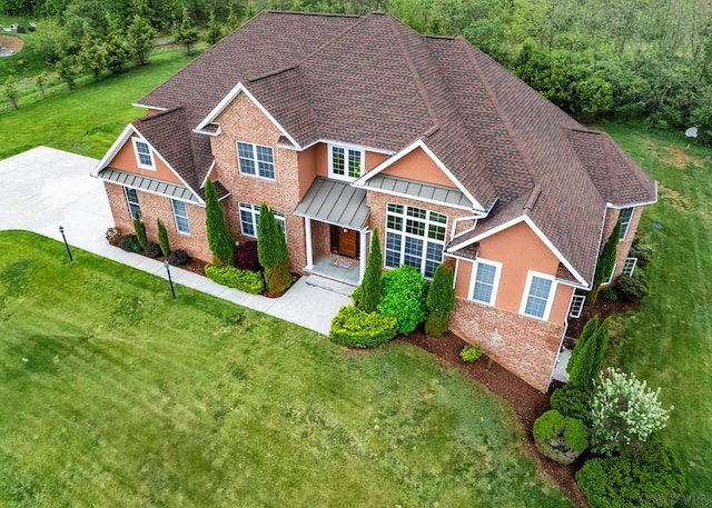 traditional home featuring brick siding, a front yard, and a shingled roof