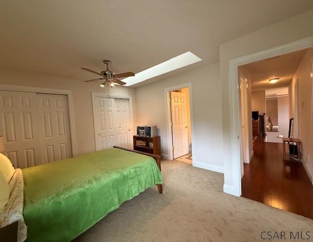 bedroom with two closets, baseboards, carpet floors, and ceiling fan
