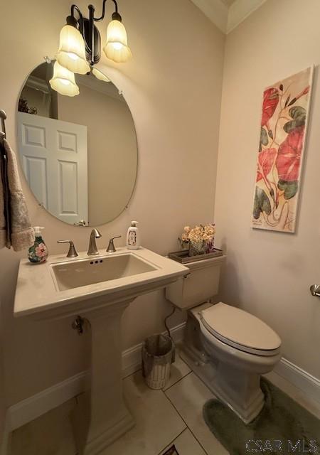 half bath featuring toilet, baseboards, tile patterned floors, and a sink