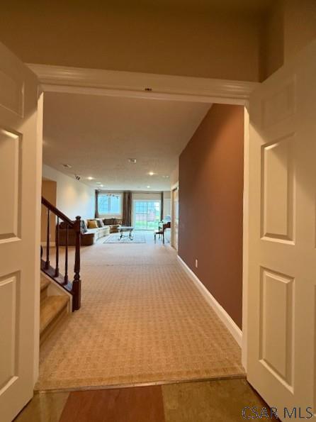 hallway featuring carpet, stairway, and baseboards