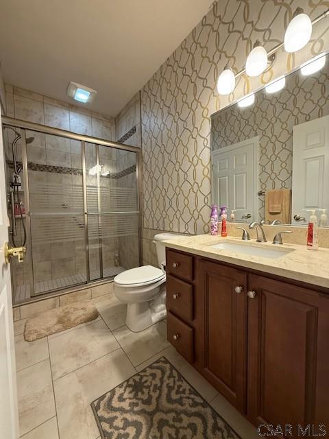 full bathroom featuring wallpapered walls, vanity, a shower stall, tile patterned flooring, and toilet