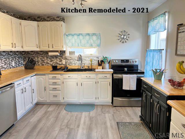 kitchen featuring a sink, white cabinetry, stainless steel appliances, light wood finished floors, and light countertops