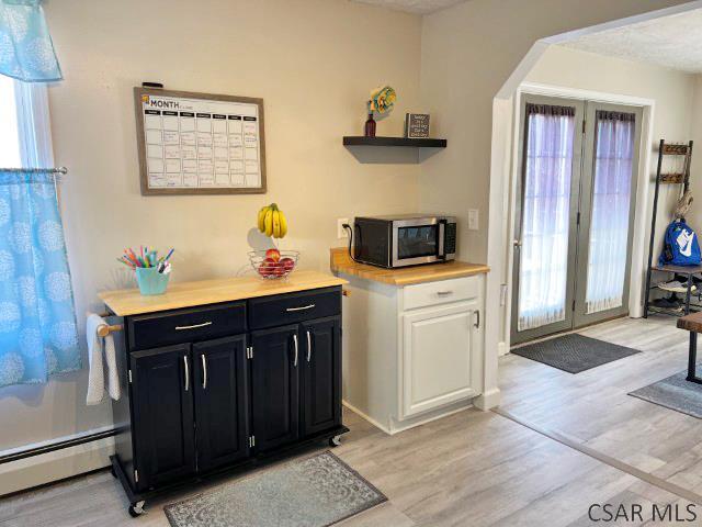 kitchen featuring stainless steel microwave, light wood-style floors, dark cabinets, and a baseboard radiator