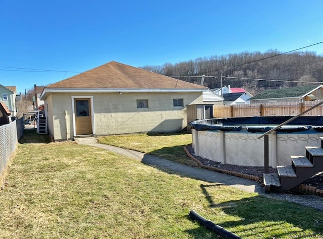 back of property featuring a fenced in pool, a lawn, concrete block siding, and a fenced backyard