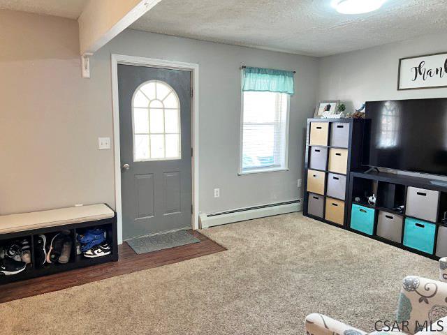 carpeted entryway with a textured ceiling and a baseboard heating unit