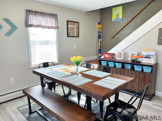 dining space featuring stairs, baseboards, and light wood finished floors