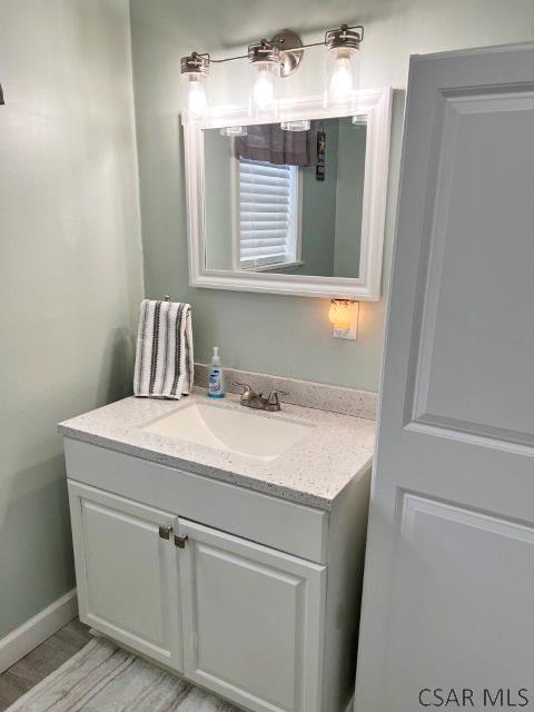 bathroom featuring vanity, wood finished floors, and baseboards