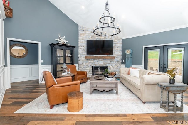 living room featuring a fireplace, lofted ceiling, a chandelier, hardwood / wood-style flooring, and french doors