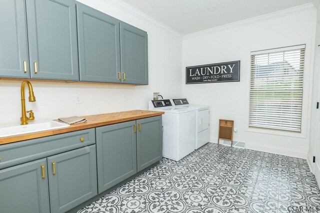 clothes washing area featuring crown molding, cabinets, separate washer and dryer, and sink