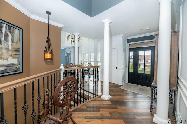 entrance foyer featuring decorative columns, crown molding, and dark hardwood / wood-style flooring