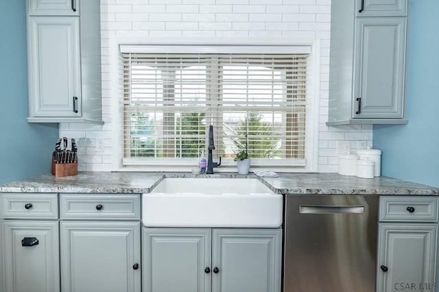 kitchen featuring tasteful backsplash, sink, stainless steel dishwasher, and gray cabinetry