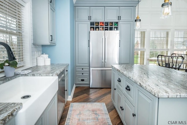 kitchen with light stone counters, stainless steel appliances, dark hardwood / wood-style flooring, and hanging light fixtures