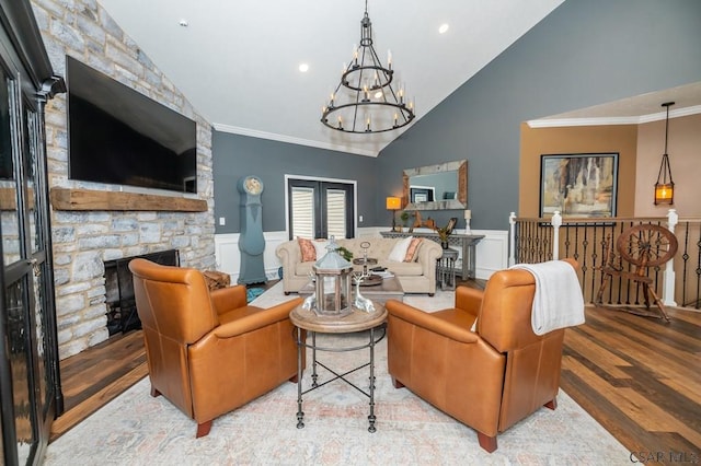 living room with a notable chandelier, a stone fireplace, lofted ceiling, and light hardwood / wood-style flooring